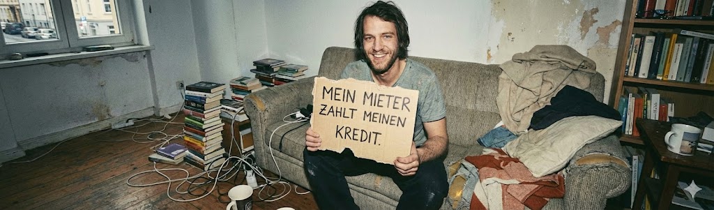 Hand hält Hausschlüssel vor einem Gebäude